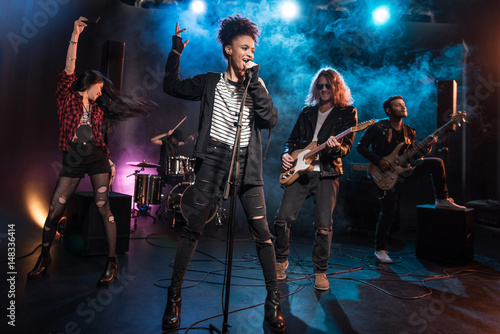 Fotografia Female singer with microphone and rock and roll band performing hard rock music