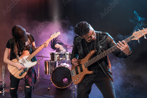 Fototapeta Rock and roll band with electric guitars playing hard rock music on stage