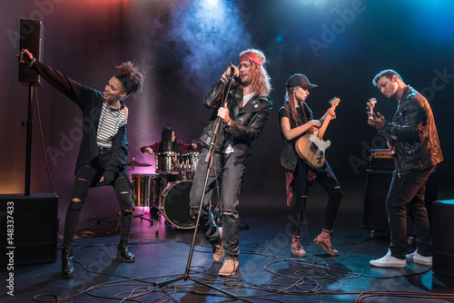Young multiethnic rock and roll band performing music on stage