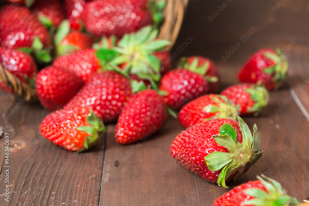 Fresh strawberry falled out of basket over brown wooden background