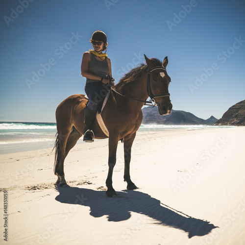 junge Frau reitet mit Pferd am Strand
