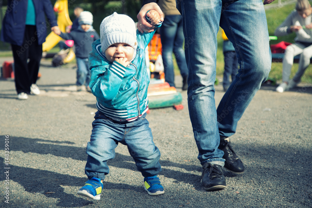 Father and son walking in the park on summer day. Little child holding hand of a man Father and son walking in the park on summer day. Little child holding hand of a man