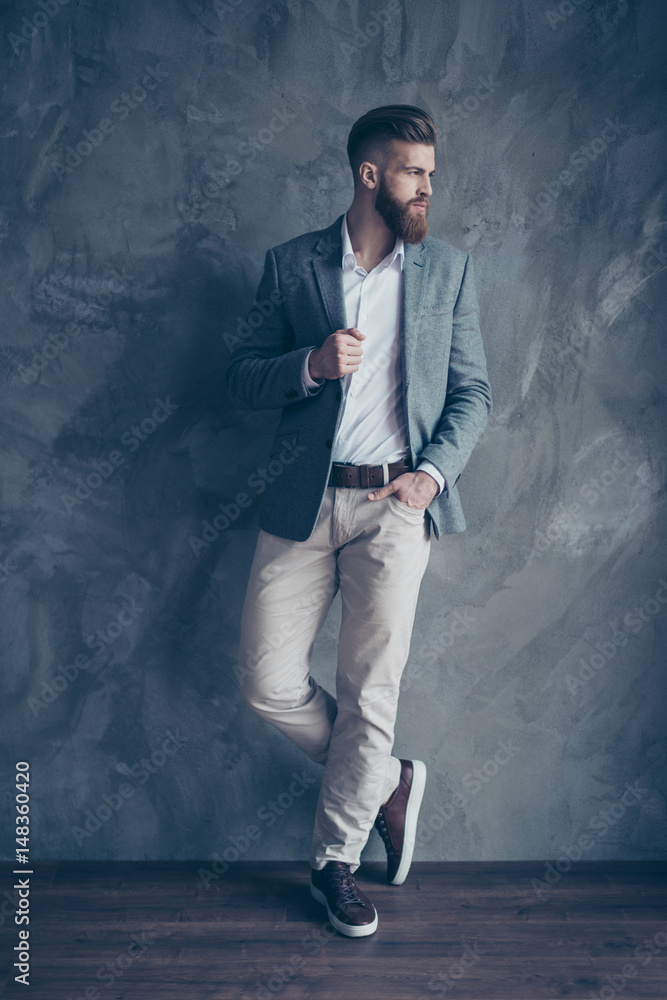Full size portrait of stylish young man standing on gray background. Profile view of model Full size portrait of stylish young man standing on gray background. Profile view of model