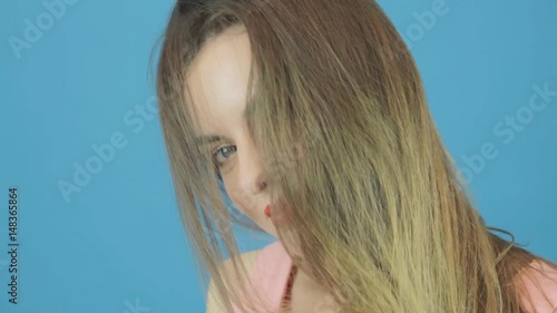 Amazing Woman with Long Dark Hair, Pink Dress and Charming Smile Posing in Studio on Blue Background.