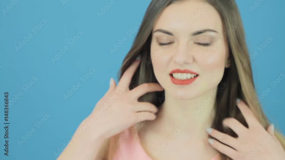 Cute Young Woman is Posing on Blue Background. Brunette with Long Hair in Studio.