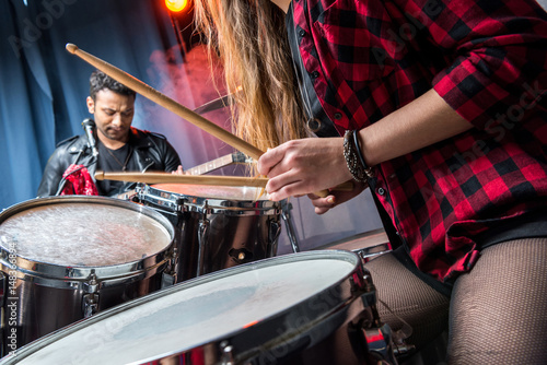 partial view of woman playing drums with man playing guitar, rock band concept