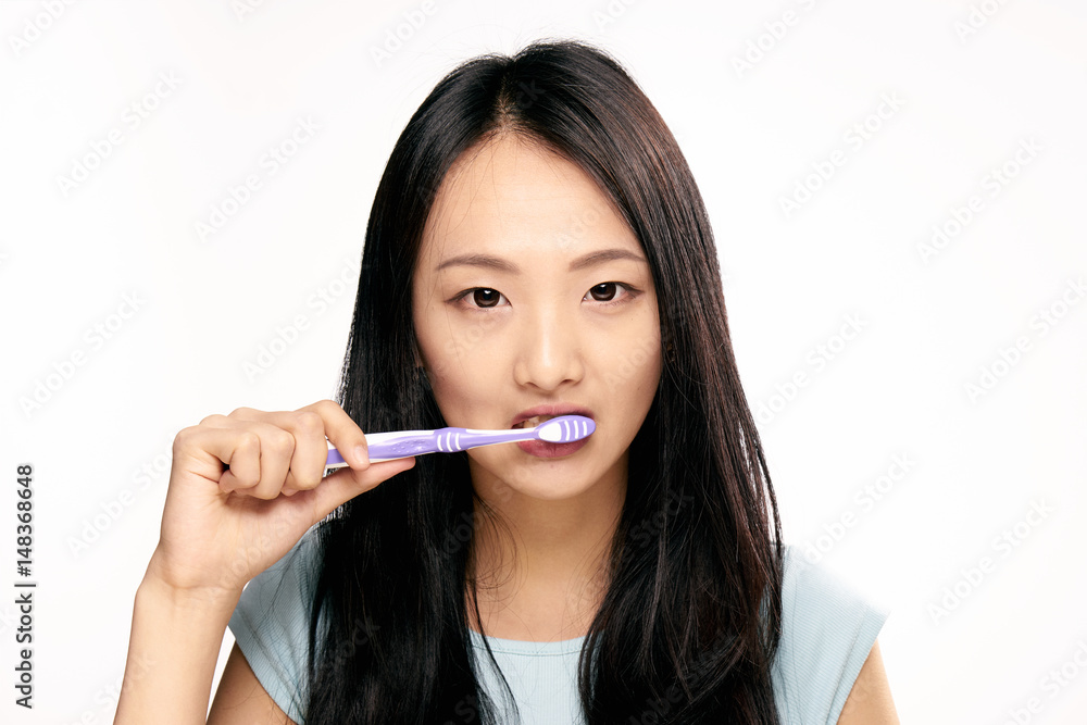 woman, narrow eyes, brush your teeth against a light background woman, narrow eyes, brush your teeth against a light background