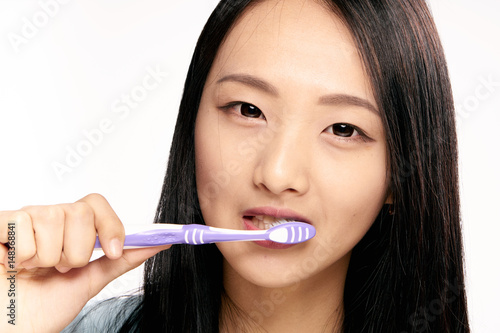 woman, narrow eyes, brush your teeth against a light background