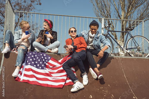 teenagers having fun with american flag in skateboard park, hipster students concept © LIGHTFIELD STUDIOS