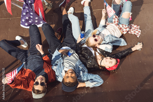 elevated view of teenagers having fun and lying with american flag in skateboard park  hipster style concept