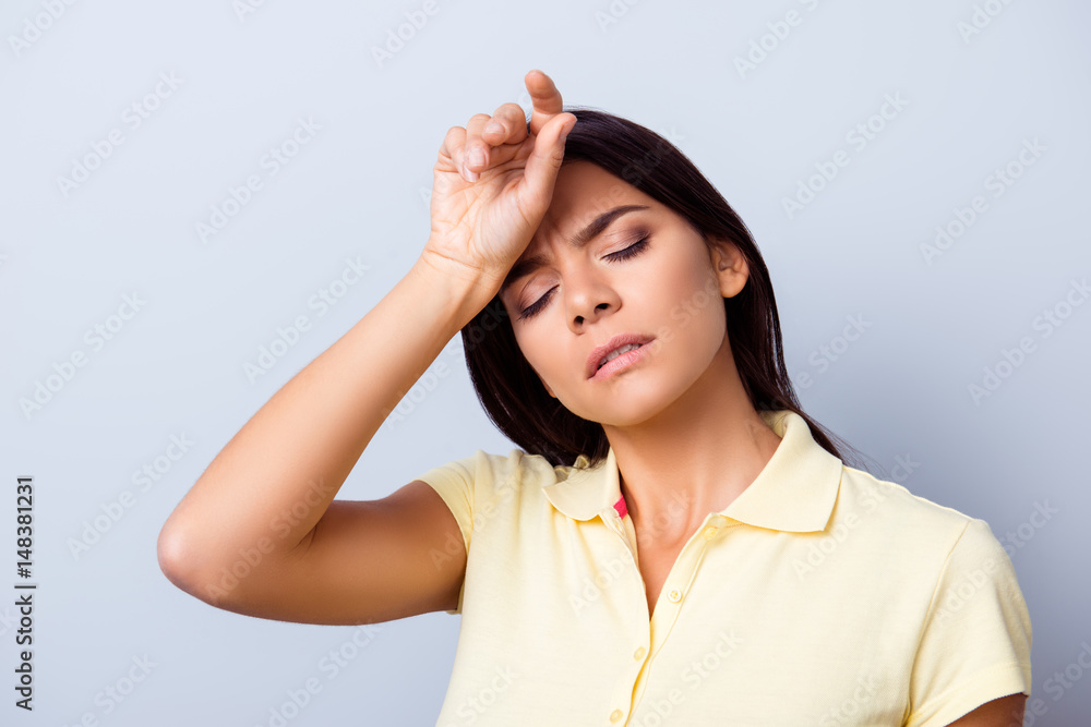 Fototapeta premium Young hispanic lady in a casual clothes on light blue background is holding her hand near the forehead. She is tired and don`t feel well