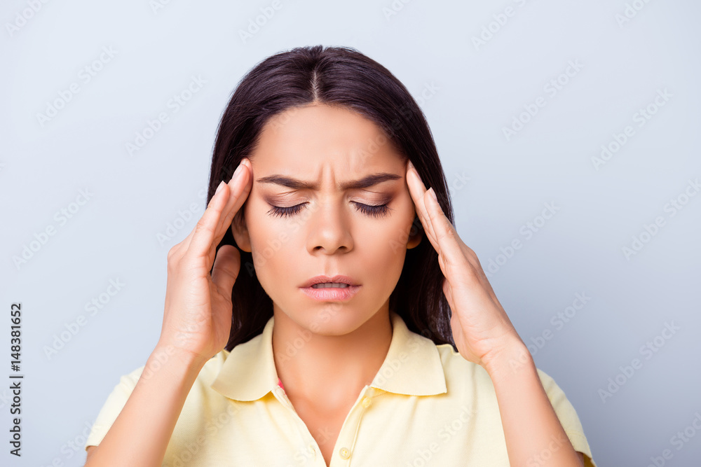 Close up portrait of a young pretty hispanic woman having headache after stressful workday and touching her temples Close up portrait of a young pretty hispanic woman having headache after stressful workday and touching her temples