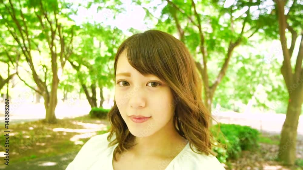 見つめる　若い女性　新緑の公園　瞬き