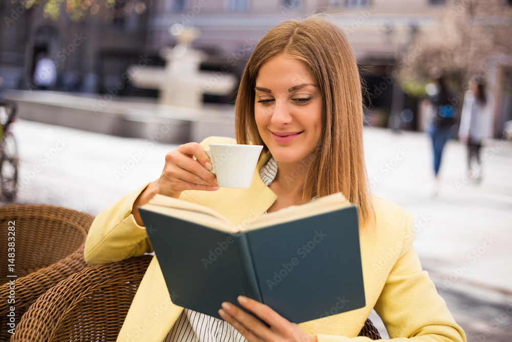 Beautiful young woman enjoys drinking coffee and reading book at the cafe. Beautiful young woman enjoys drinking coffee and reading book at the cafe.