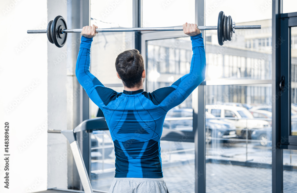 Fototapeta premium Handsome young man workout with barbell at gym