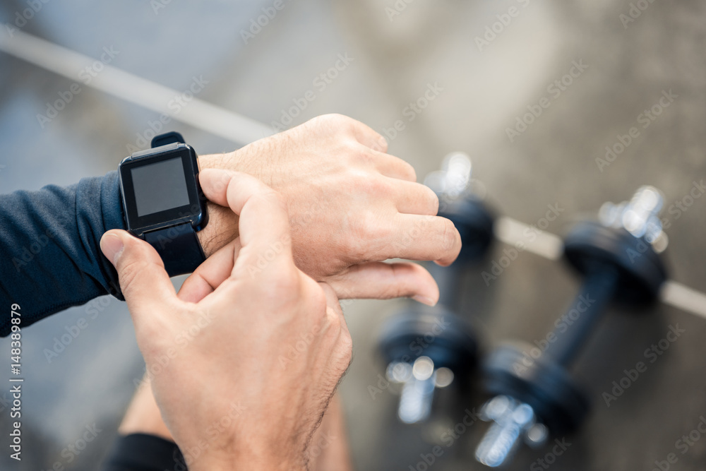 Handsome young man using smartwatch at gym
