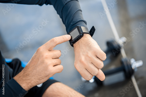 Handsome young man using smartwatch at gym