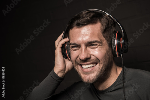 Handsome young man listening music in headphones, isolated on black