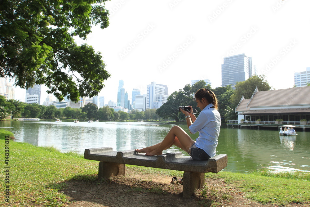 Young Asian woman sit on stone chair near the river with tree on background