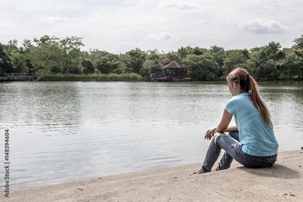 Young Asian woman sit near the Lake.