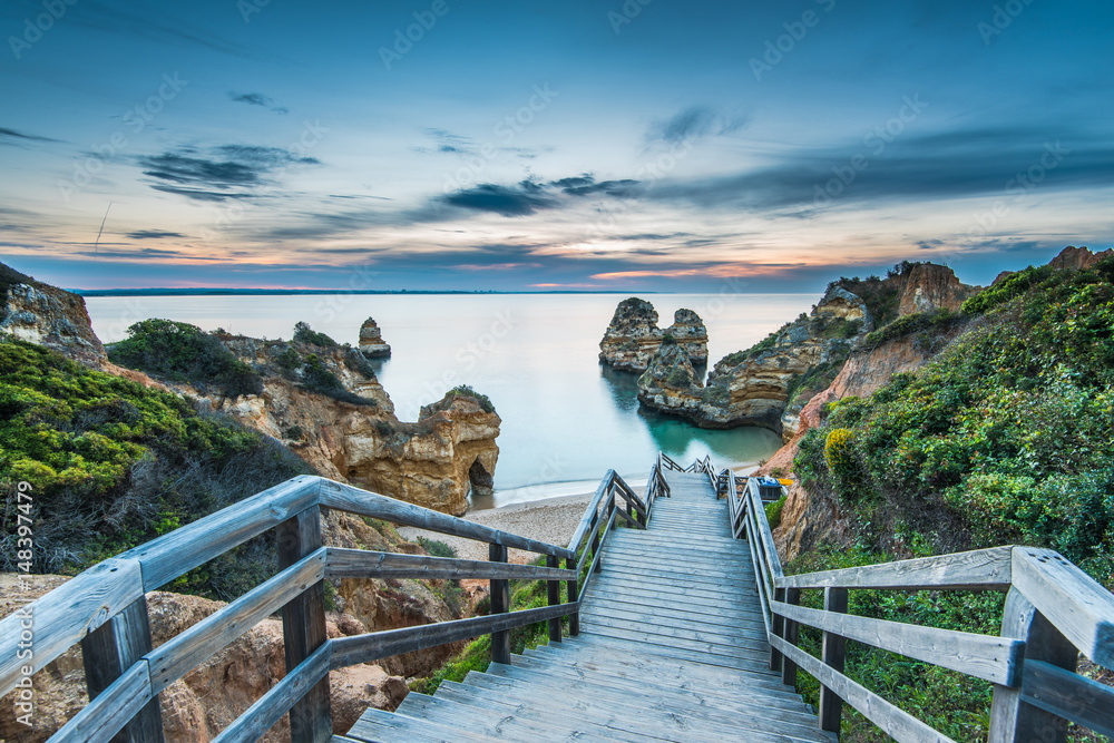 Wooden footbridge walkway to beautiful beach Praia do Camilo on coast of Algarve region, Portugal - obrazy, fototapety, plakaty 