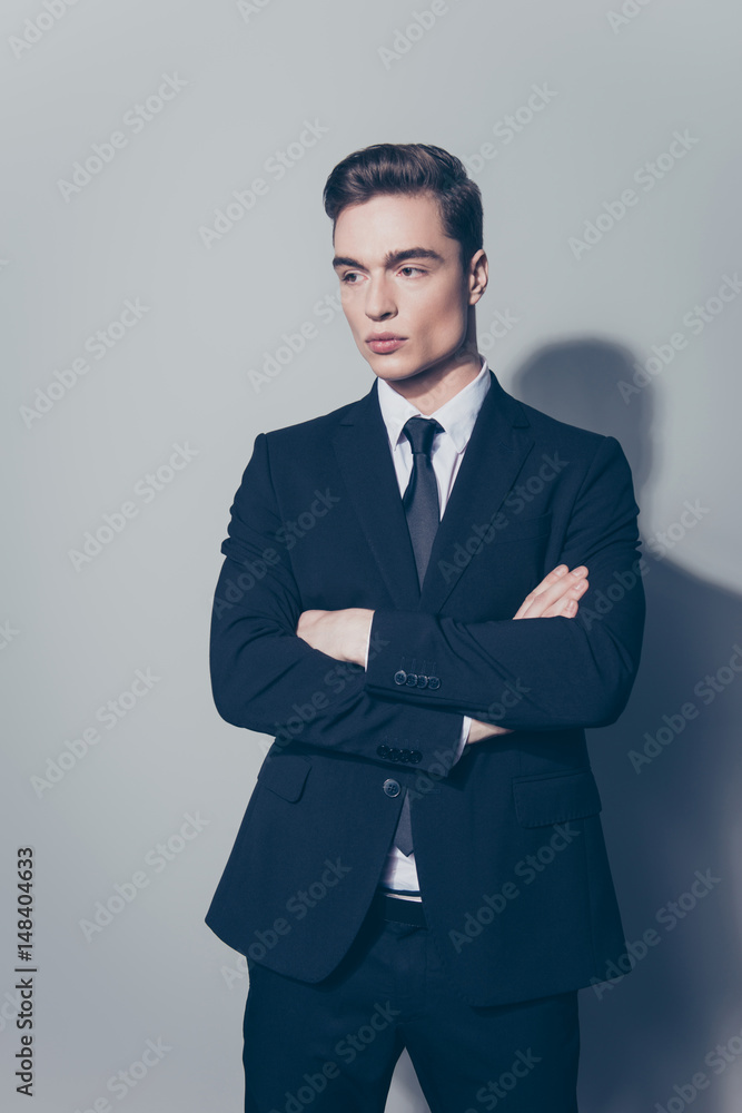 Young attractive businessman is standing on the pure light background. He looks stunning! So severe and confident Young attractive businessman is standing on the pure light background. He looks stunning! So severe and confident