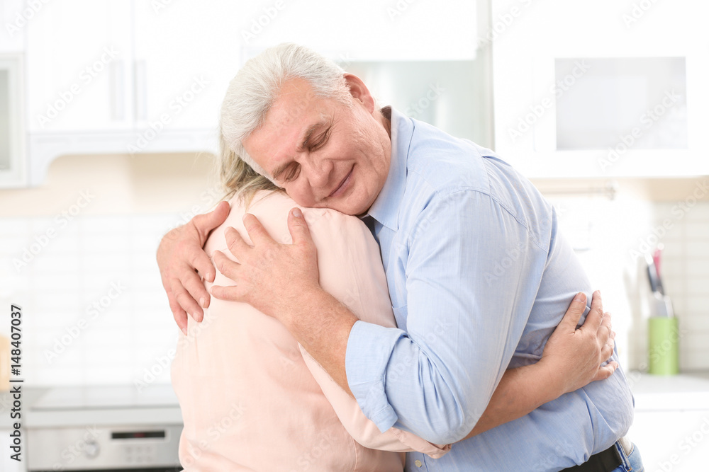 Middle aged couple embracing at kitchen Middle aged couple embracing at kitchen