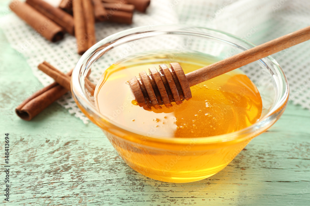Cinnamon and honey in glass bowl on table, closeup Cinnamon and honey in glass bowl on table, closeup