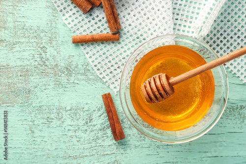Cinnamon and honey in bowl on wooden background, top view