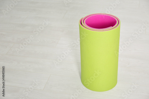 Rolled up yoga mat on wooden floor