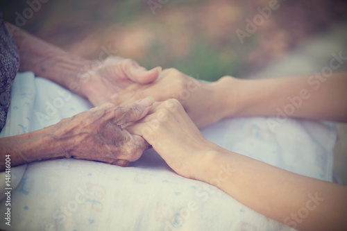 Old and young holding hands on light background  vintage tone.