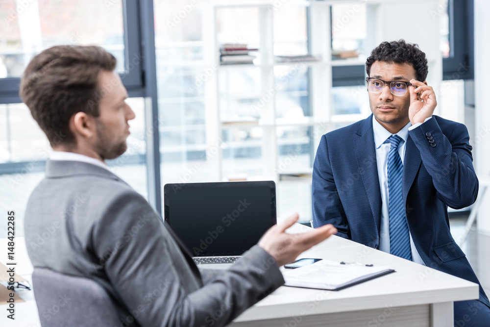 Two businessmen in formal wear sitting and talking at job interview, business concept