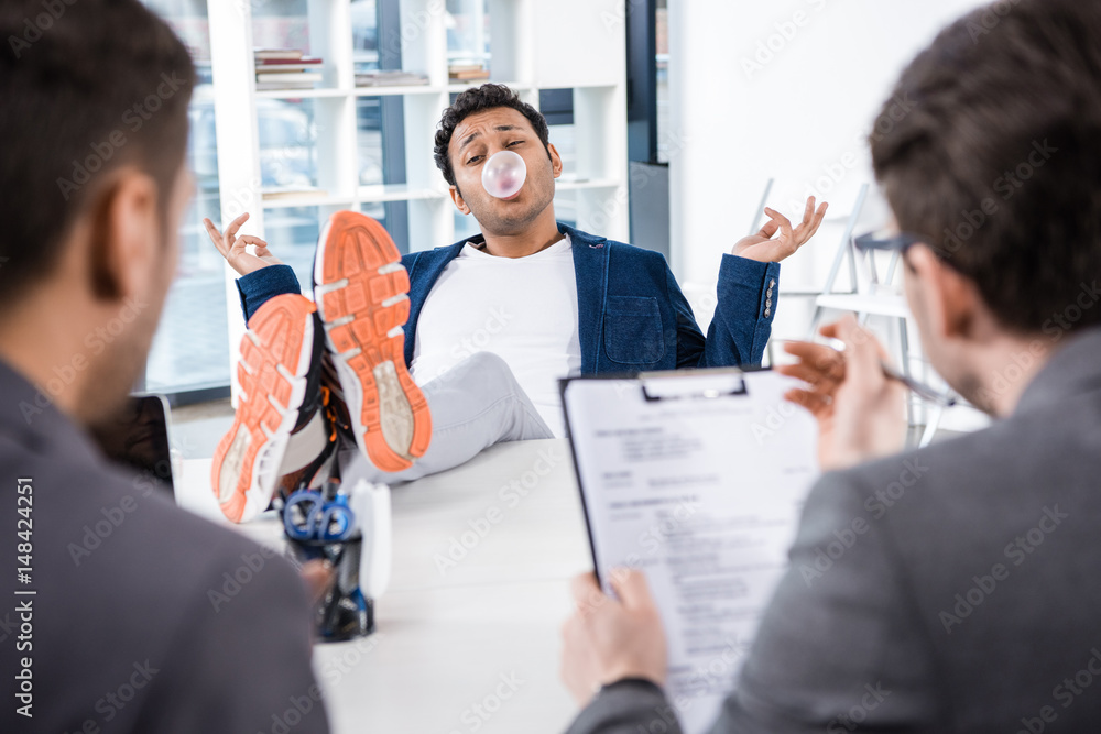Fotografie businessman blowing bubble gum with legs on table during job interview, business