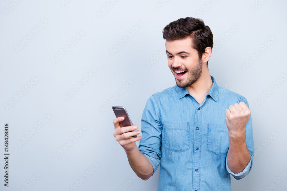 Portrait of very happy hansome brunet reading a message on his pda and celebrating victory Portrait of very happy hansome brunet reading a message on his pda and celebrating victory
