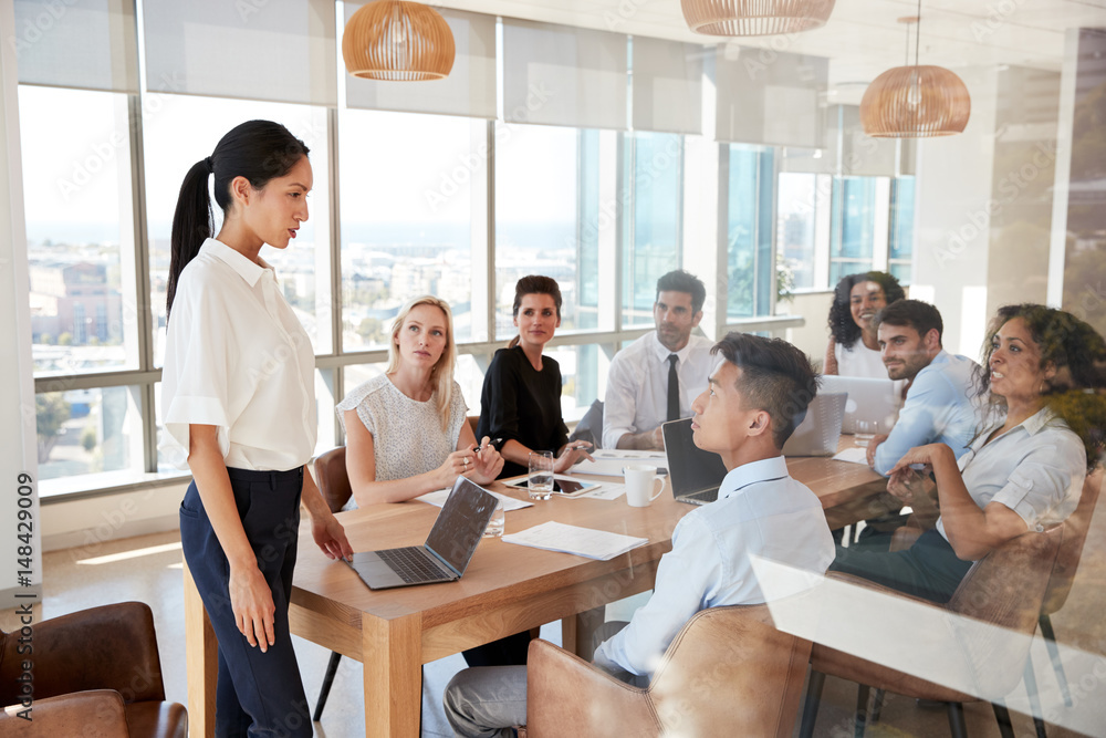 Businesswoman Leads Meeting Around Table Shot Through Door Businesswoman Leads Meeting Around Table Shot Through Door