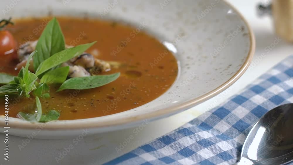 Tomato soup with seafood decorated with basil leaves and cherry tomatoes in white plate on the table. Tomato soup with seafood decorated with basil leaves and cherry tomatoes in white plate on the table.