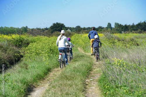 Back view of family riding bicycles on country track