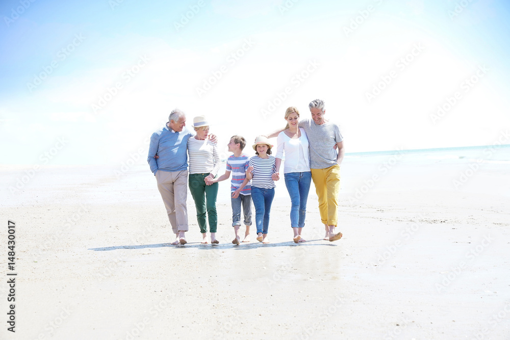 Family, parents, grandparents and grandkids walking on the beach