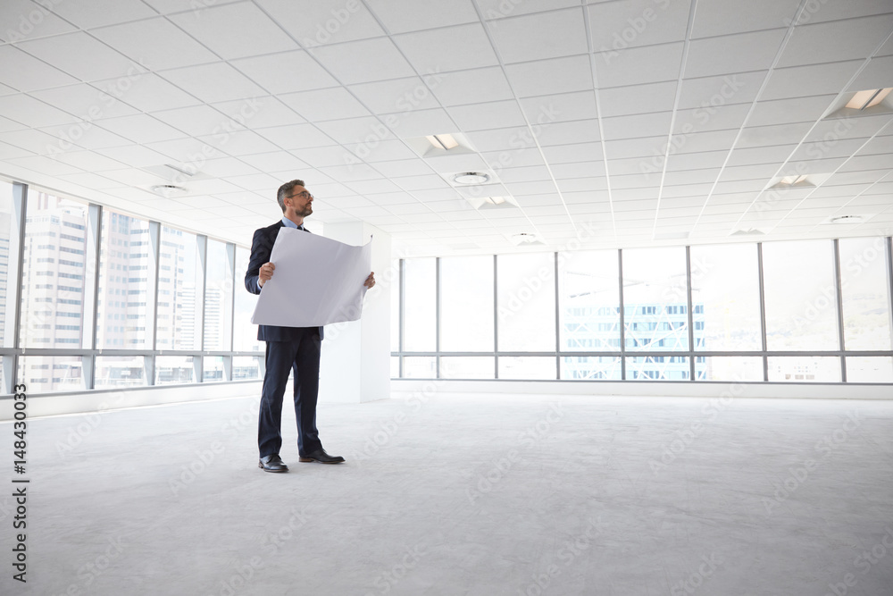 Male Architect In Modern Empty Office Looking At Plans