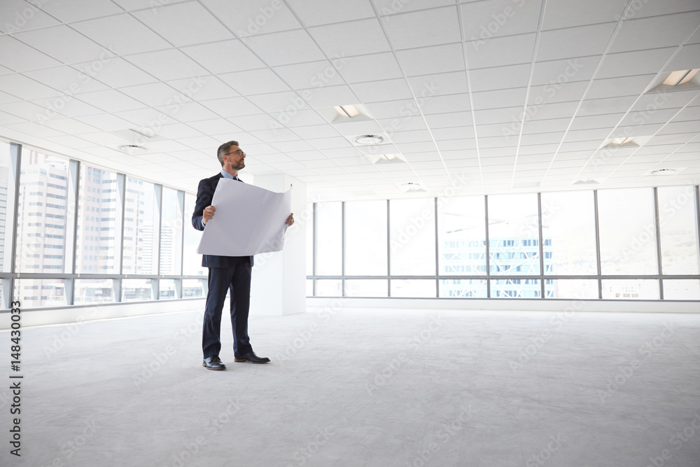 Male Architect In Modern Empty Office Looking At Plans Male Architect In Modern Empty Office Looking At Plans