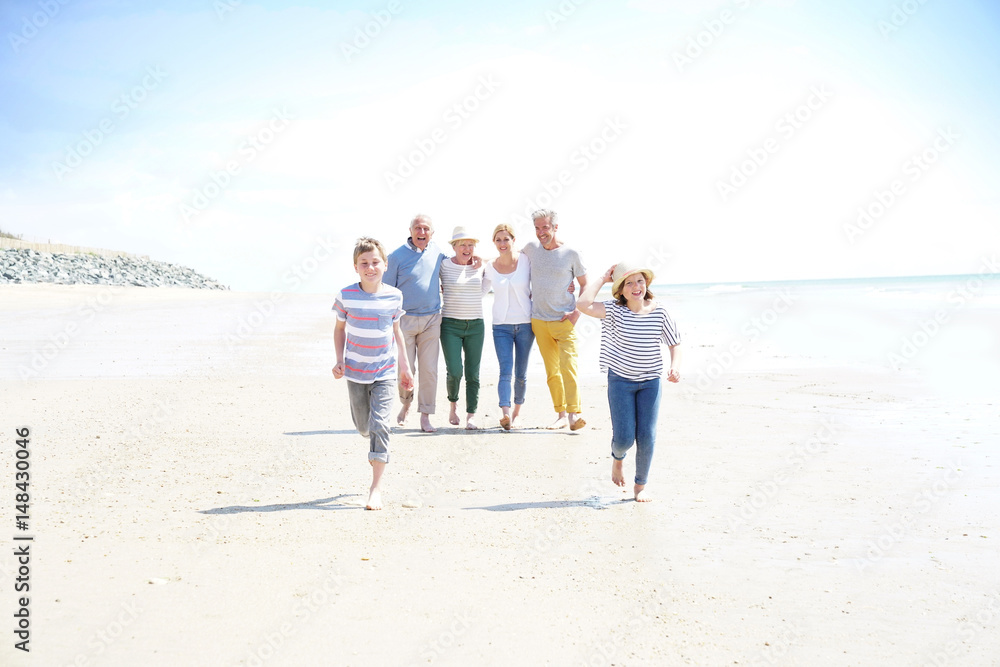 Family, parents, grandparents and grandkids walking on the beach