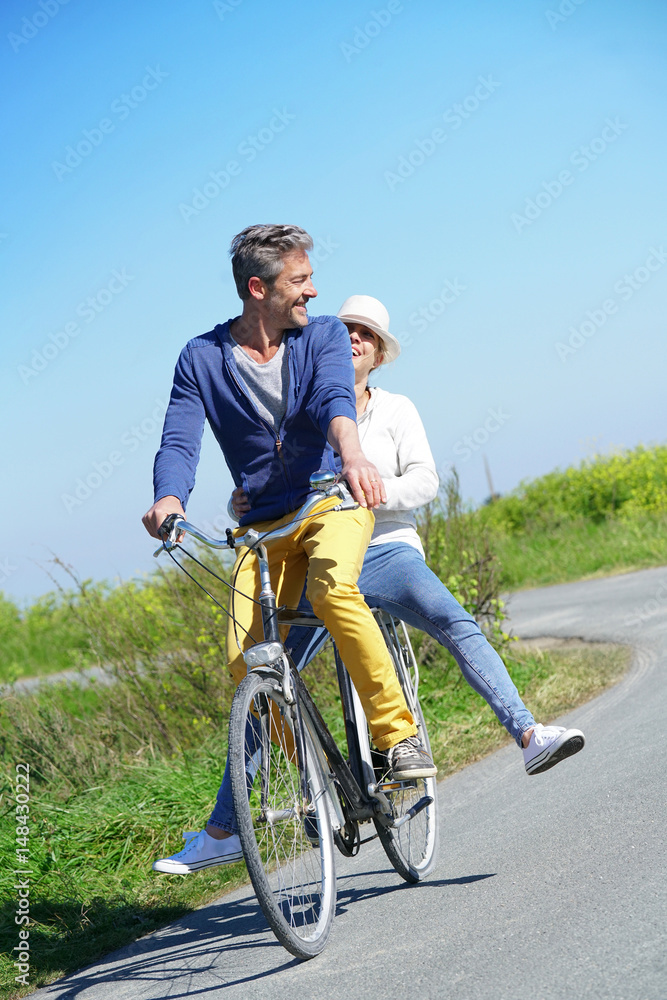 Obraz premium Cheerful couple riding bike on a sunny day