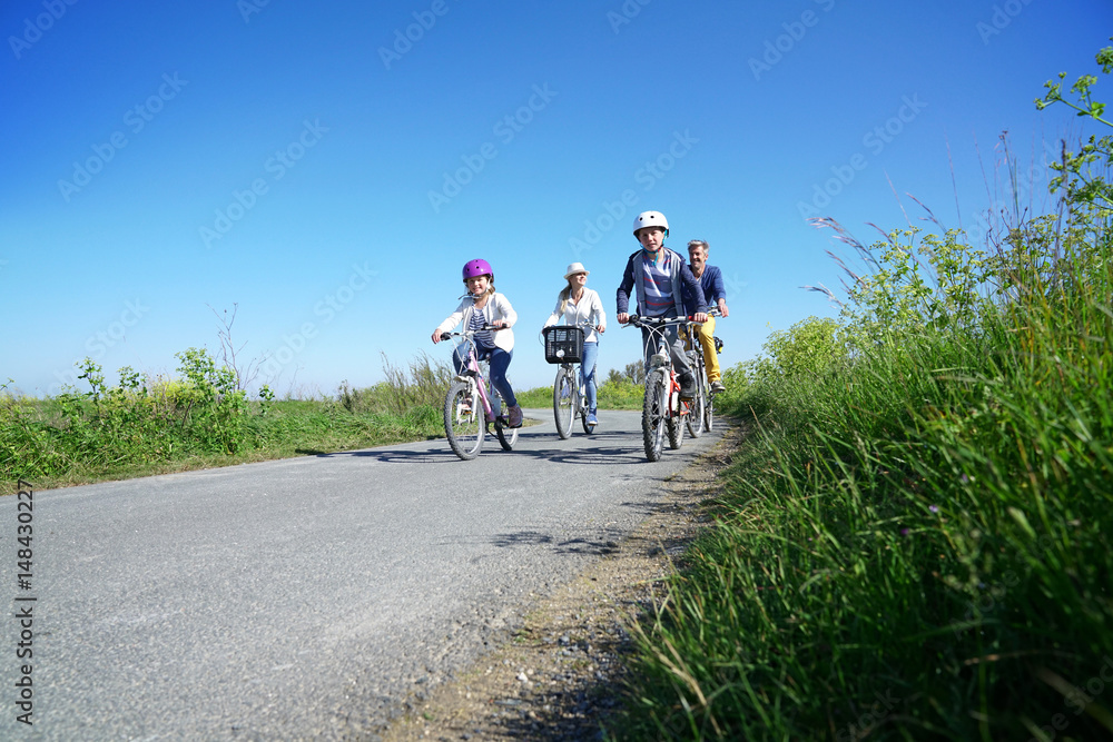 Naklejka premium Happy family riding bikes on week-end in countryside