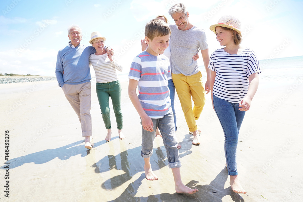 Happy intergenerational family walking on the beach Stock Photo | Adobe ...