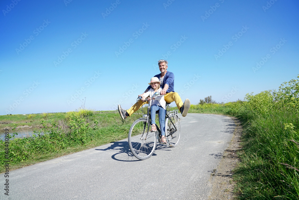 Obraz premium Father and daughter having fun riding bike together
