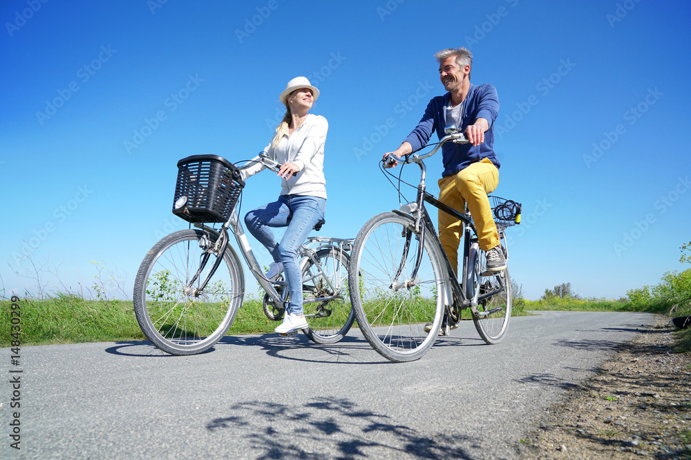Obraz premium Cheerful couple riding bike on a sunny day