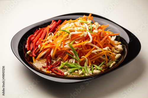Fresh vegetable salad with peppers, carrots, sprouts, nuts, herbs and seeds. Healthy vegetarian food on light background. Theme of raw food, live and healthy eating