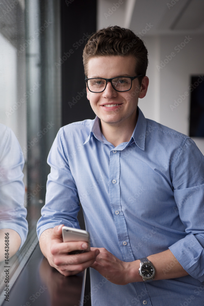 Businessman Standing In A Modern Building Near The Window With Phone Businessman Standing In A Modern Building Near The Window With Phone