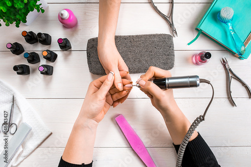 Manicure for the client. Close-up of the hands of a manicurist and client on a wooden background