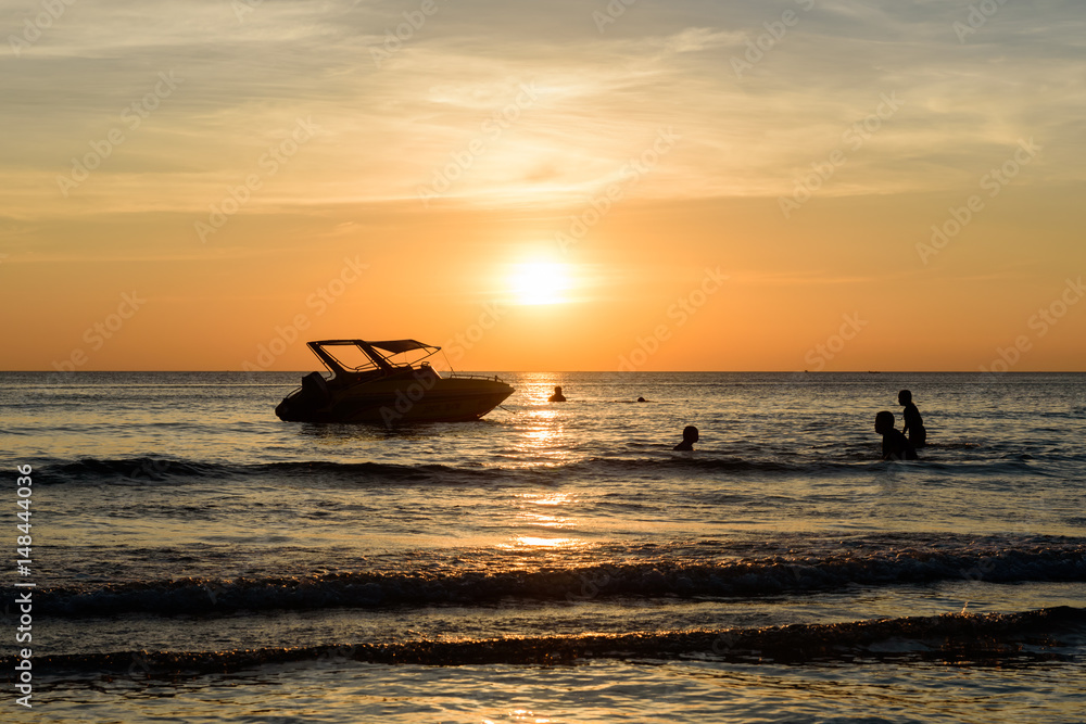 Chao Lao Beach at Chanthaburi  Dec 18,2016 : People swim near shadow boat and light sunset on the beach,THAILAND